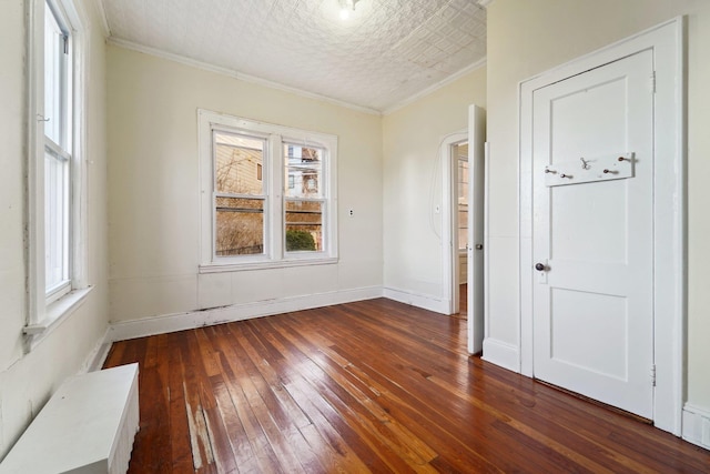 spare room featuring a textured ceiling, dark hardwood / wood-style flooring, and ornamental molding