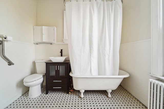 bathroom with toilet, radiator, tile patterned flooring, sink, and a tub to relax in