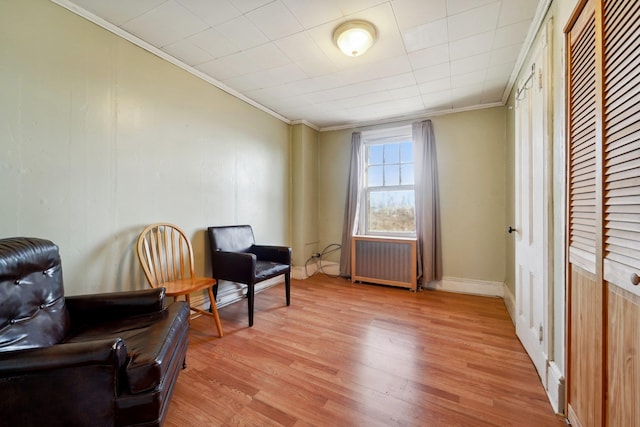 living area featuring radiator, ornamental molding, and light wood-type flooring