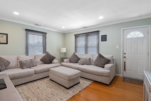 living room with light wood-type flooring and ornamental molding