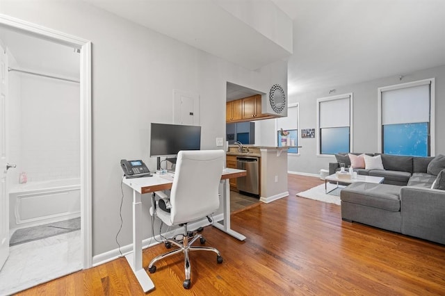 office area featuring wood finished floors, baseboards, and a sink