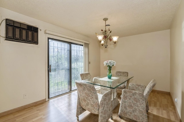 dining space with a textured ceiling, a notable chandelier, and light wood-type flooring