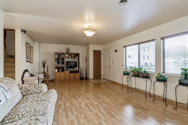 living room featuring visible vents, stairway, baseboards, and light wood-style floors