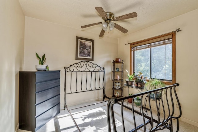 interior space featuring baseboards, a textured ceiling, and a ceiling fan