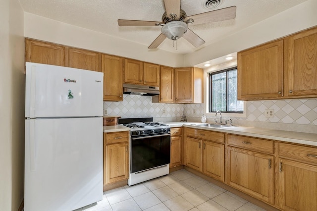 kitchen with under cabinet range hood, white appliances, light countertops, and a sink