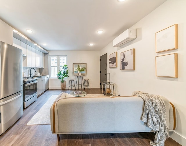 living room featuring sink, a wall unit AC, and hardwood / wood-style floors