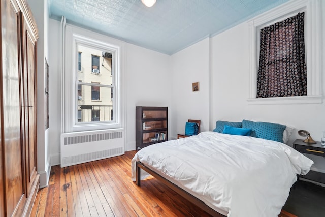 bedroom featuring an ornate ceiling, radiator, and light wood-style flooring