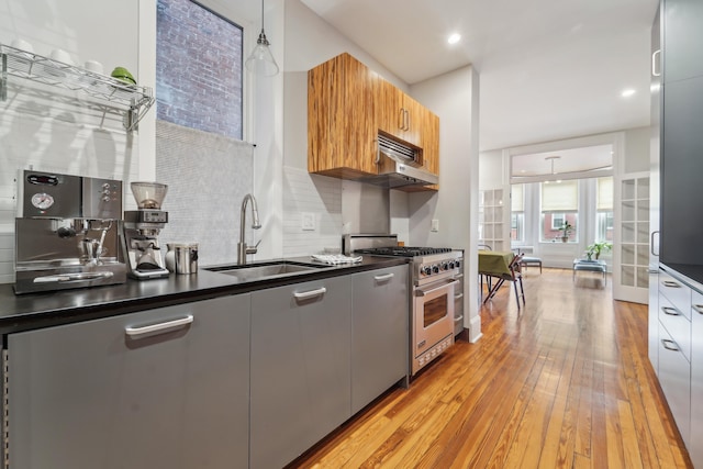 kitchen featuring dark countertops, modern cabinets, high end stainless steel range, and a sink