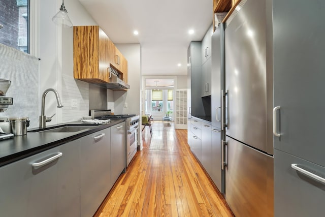 kitchen with a sink, stainless steel appliances, dark countertops, and modern cabinets