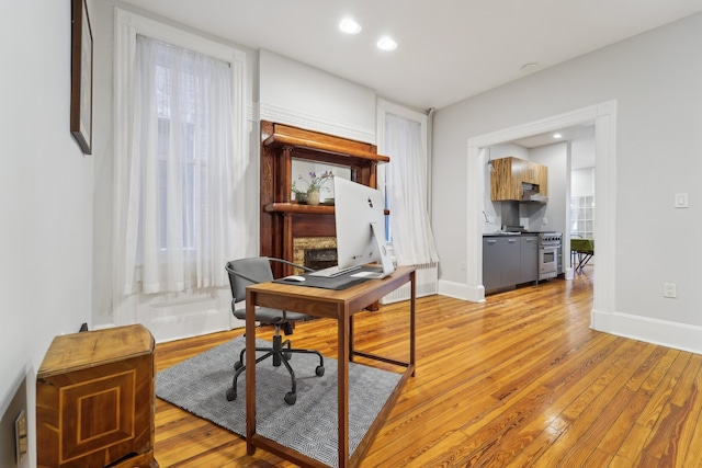 home office with recessed lighting, light wood-style flooring, and baseboards