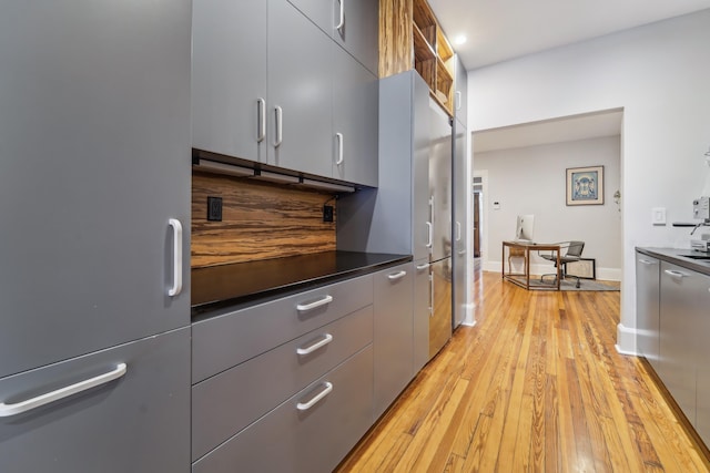 kitchen featuring dark countertops, modern cabinets, light wood-type flooring, and freestanding refrigerator