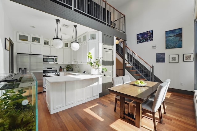 245 Ogden Ave Unit 2, Jersey City, NJ 07307 - kitchen featuring stainless steel appliances, a peninsula, wood finished floors, white cabinets, and a high ceiling