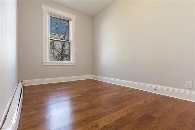 198 Myrtle Ave, Jersey City, NJ 07305 - unfurnished room featuring a baseboard heating unit and dark wood-style flooring