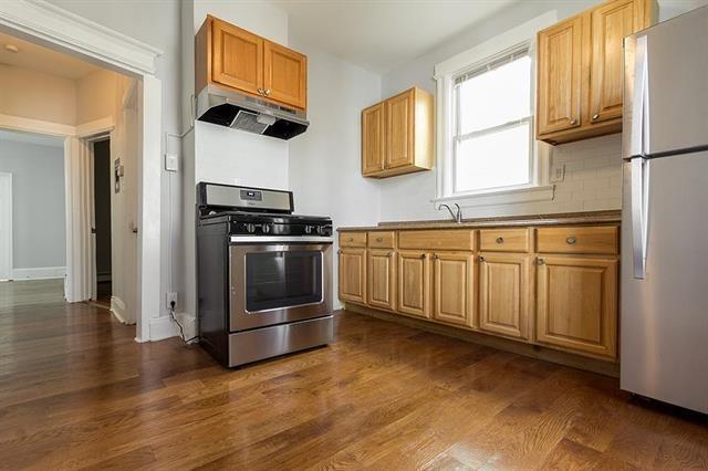 198 Myrtle Ave, Jersey City, NJ 07305 - kitchen with stainless steel gas range, under cabinet range hood, freestanding refrigerator, and dark wood-type flooring