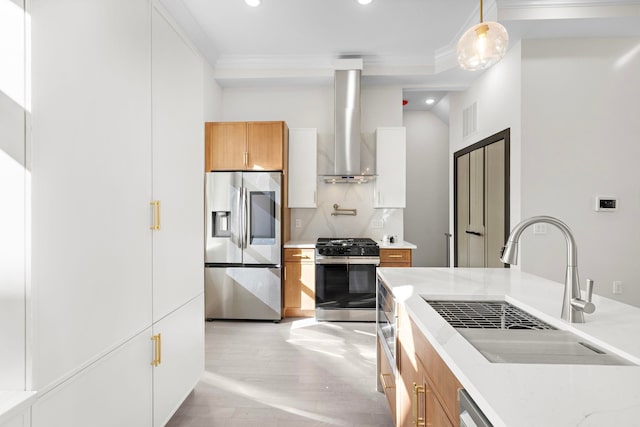 kitchen featuring appliances with stainless steel finishes, decorative light fixtures, sink, white cabinets, and wall chimney range hood