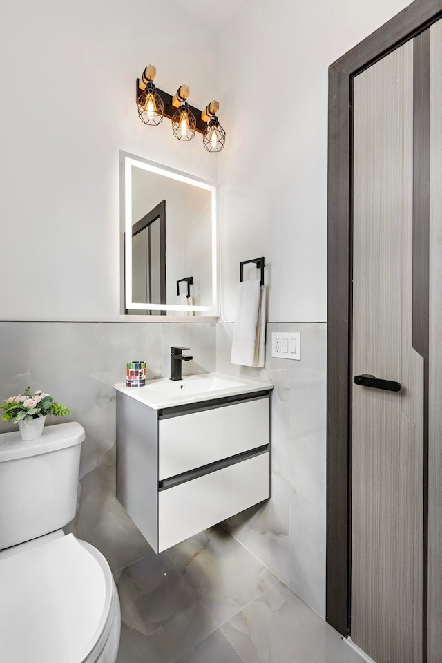 bathroom with vanity, toilet, and tile walls