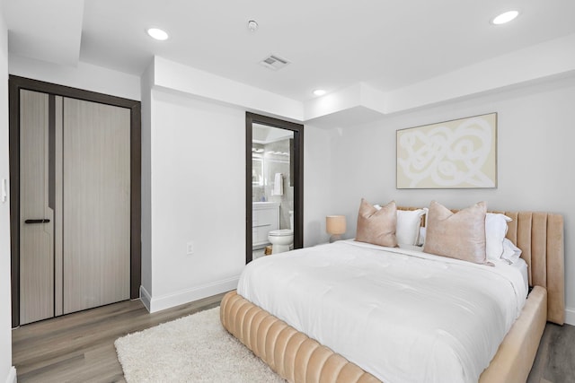 bedroom with ensuite bathroom, hardwood / wood-style floors, and a closet