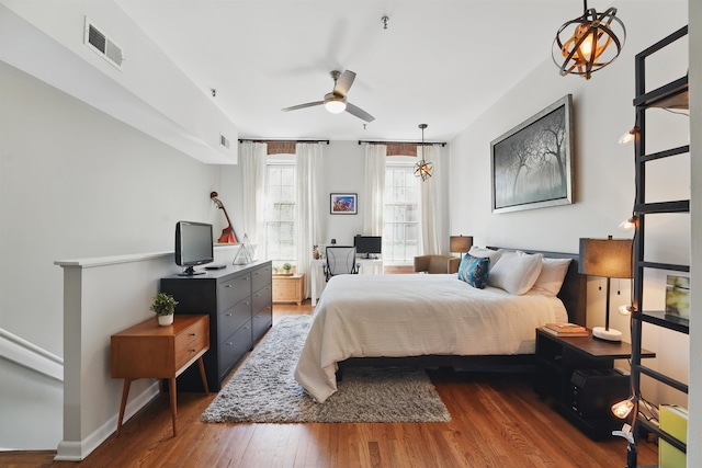 bedroom featuring baseboards, wood finished floors, and visible vents