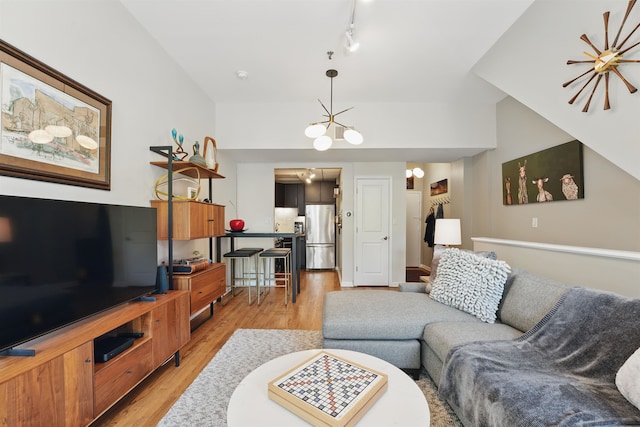 living room with light wood-style flooring, track lighting, and a notable chandelier