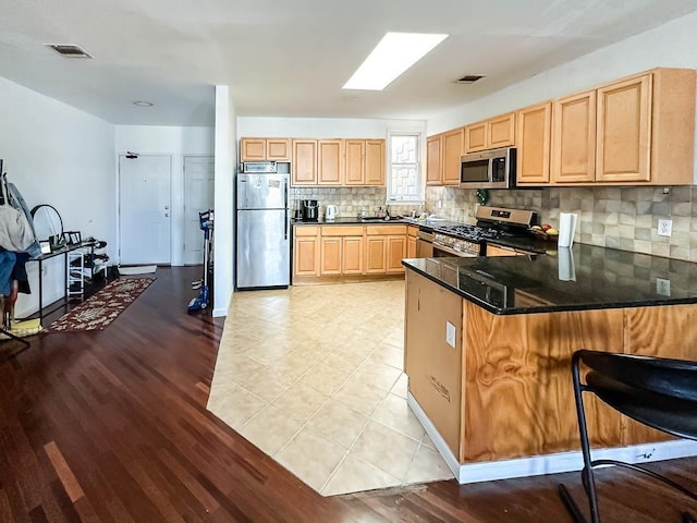 3481 John F Kennedy Blvd Unit 301, Jersey City, NJ 07307 - kitchen featuring stainless steel appliances, light brown cabinetry, a peninsula, backsplash, and light wood finished floors