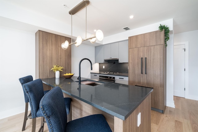 kitchen featuring pendant lighting, sink, dark stone countertops, oven, and a large island