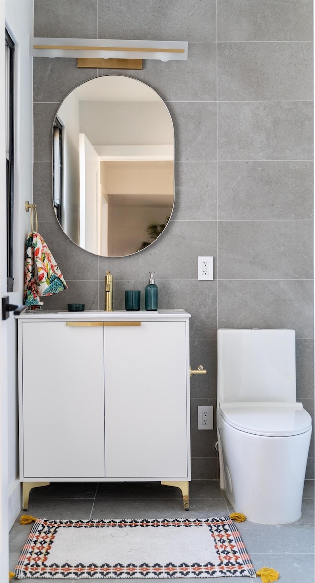 bathroom featuring vanity, toilet, tile patterned flooring, and tile walls