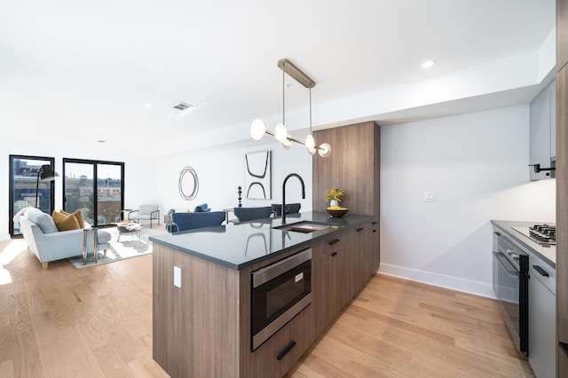 kitchen featuring stainless steel appliances, sink, light wood-type flooring, and kitchen peninsula