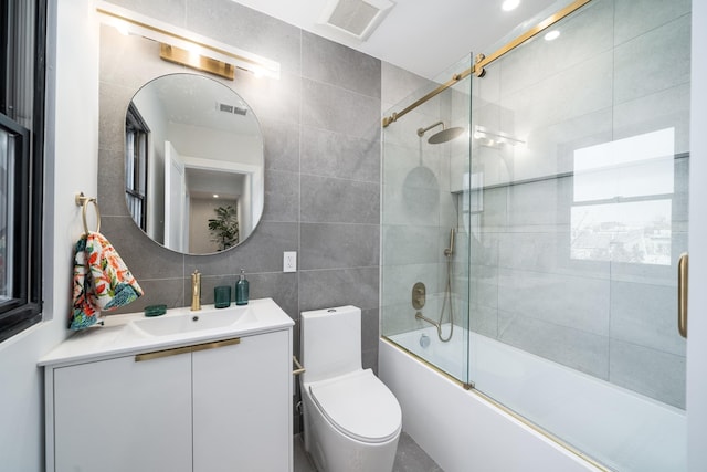 full bathroom with combined bath / shower with glass door, tasteful backsplash, tile walls, vanity, and toilet