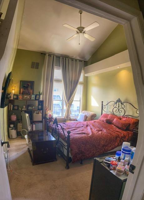 carpeted bedroom with ceiling fan and lofted ceiling