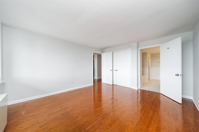 unfurnished bedroom featuring a closet, baseboards, and wood finished floors