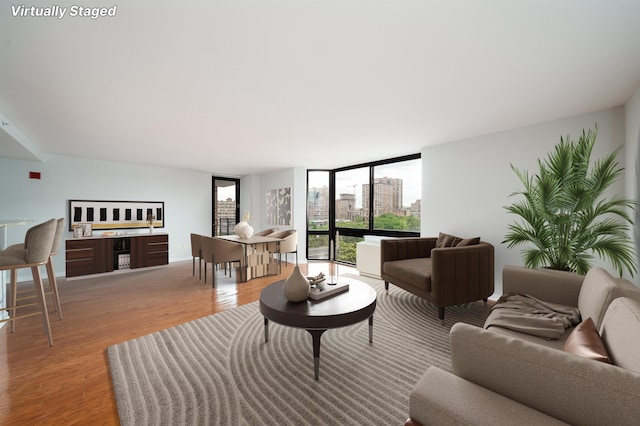 living room with light wood-type flooring, a view of city, and a wall of windows