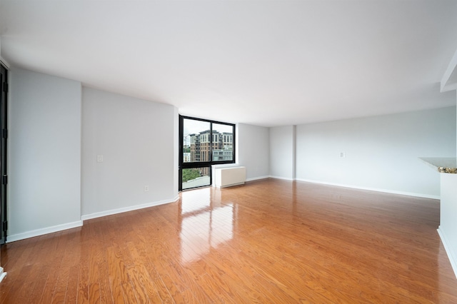 interior space with light wood-type flooring, radiator, expansive windows, and baseboards