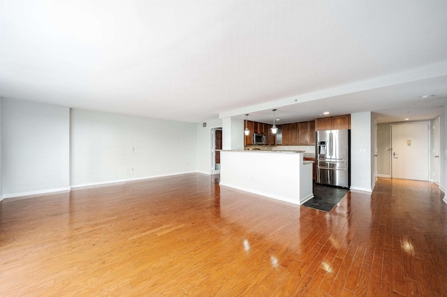 unfurnished living room featuring wood finished floors and baseboards