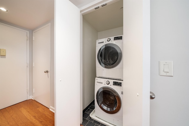 laundry area featuring stacked washer / drying machine, laundry area, and light wood-style flooring