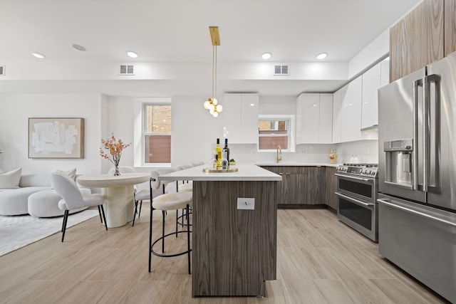 248 New York Ave Unit 1, Jersey City, NJ 07307 - kitchen featuring appliances with stainless steel finishes, modern cabinets, a kitchen breakfast bar, white cabinetry, and light countertops