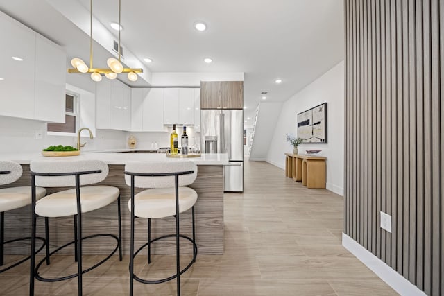 248 New York Ave Unit 1, Jersey City, NJ 07307 - kitchen with stainless steel fridge with ice dispenser, modern cabinets, a kitchen breakfast bar, a peninsula, and light countertops