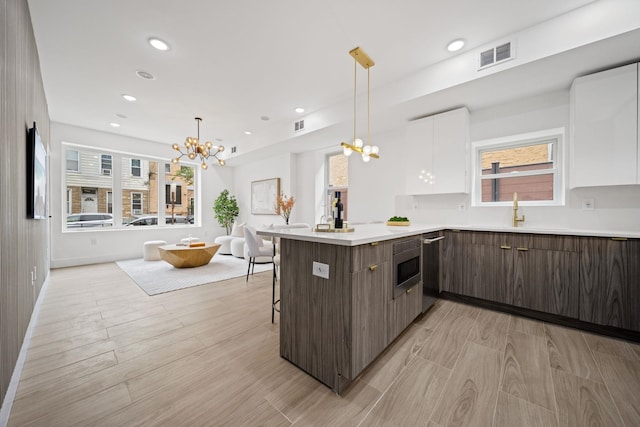 248 New York Ave Unit 1, Jersey City, NJ 07307 - kitchen with a chandelier, modern cabinets, white cabinets, a peninsula, and light countertops