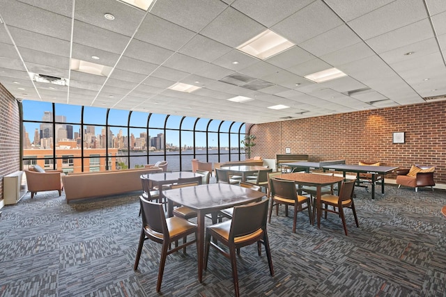 1 Greene St Unit 710, Jersey City, NJ 07302 - carpeted dining area featuring brick wall, a paneled ceiling, a view of skyline, and expansive windows