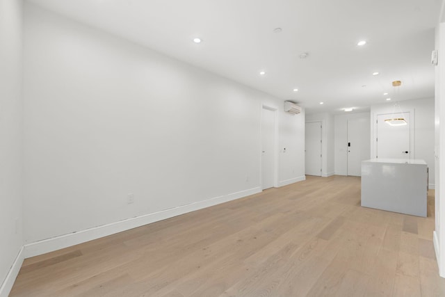 unfurnished room featuring recessed lighting, an AC wall unit, light wood-style flooring, and baseboards