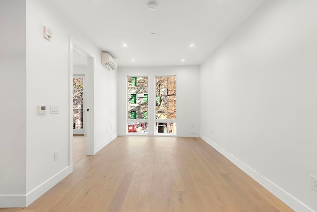 unfurnished room featuring an AC wall unit, recessed lighting, light wood-style flooring, and baseboards