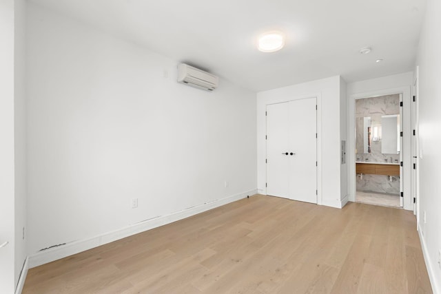 unfurnished room featuring light wood finished floors, baseboards, and a wall mounted AC