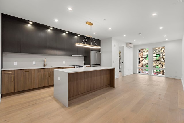 kitchen featuring freestanding refrigerator, a sink, a large island, and modern cabinets