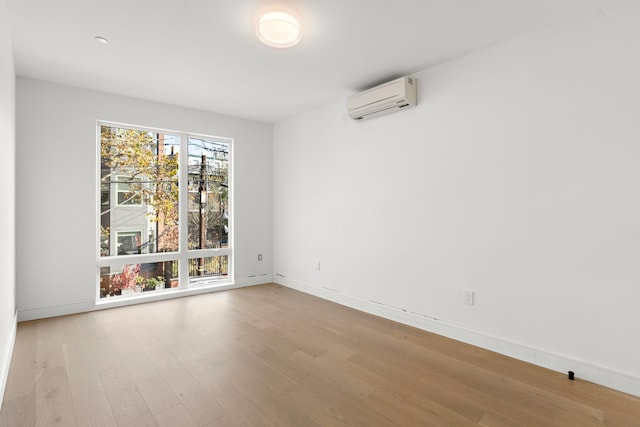 unfurnished room featuring baseboards, an AC wall unit, and wood finished floors