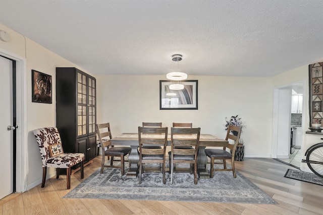 dining room featuring wood-type flooring and a textured ceiling