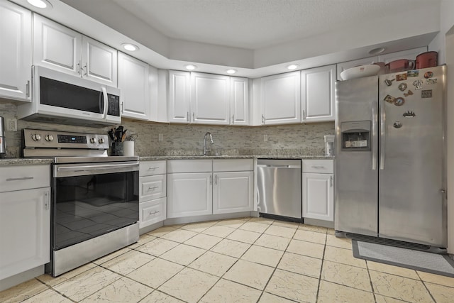 kitchen with white cabinets, backsplash, and stainless steel appliances