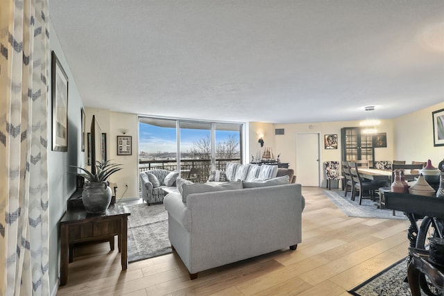 living room featuring a textured ceiling, light wood-type flooring, and floor to ceiling windows