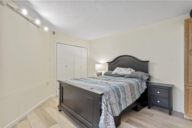 bedroom featuring a closet, light hardwood / wood-style floors, and a textured ceiling