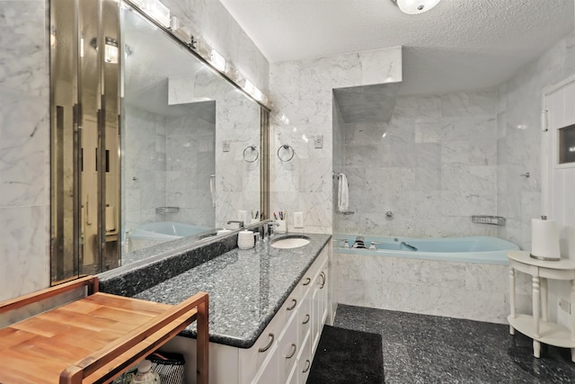 bathroom featuring a textured ceiling, vanity, tile walls, and tiled bath