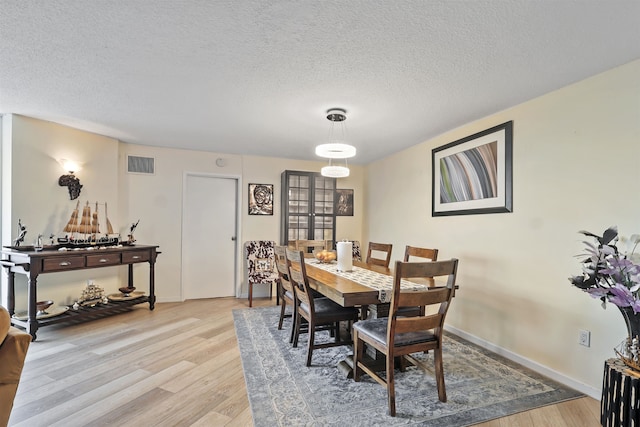 dining area featuring light hardwood / wood-style floors and a textured ceiling