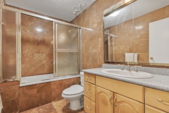 full bathroom featuring vanity, a textured ceiling, tile walls, enclosed tub / shower combo, and toilet